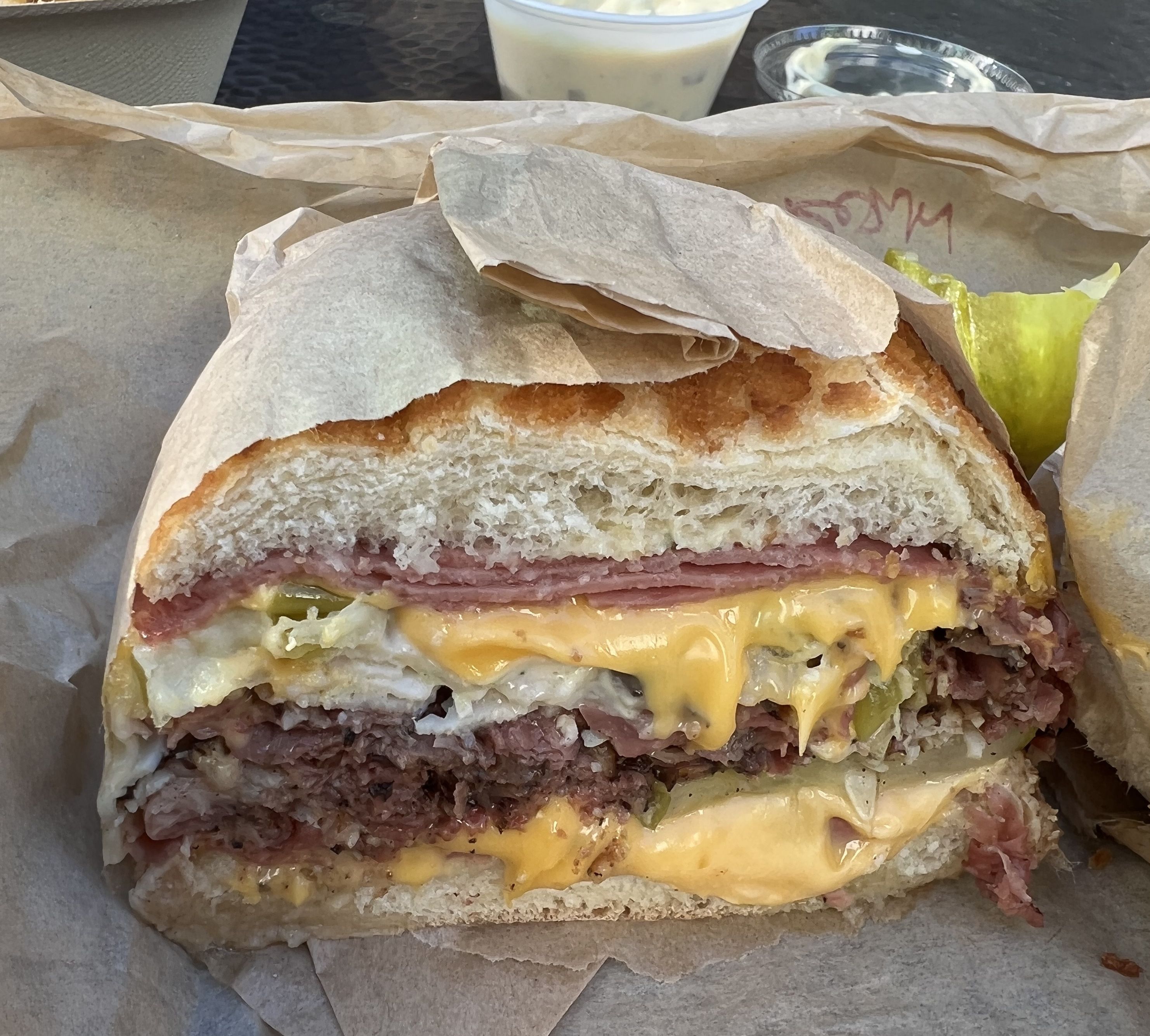 A sandwich with pastrami cheese and pickles on dutch crunch